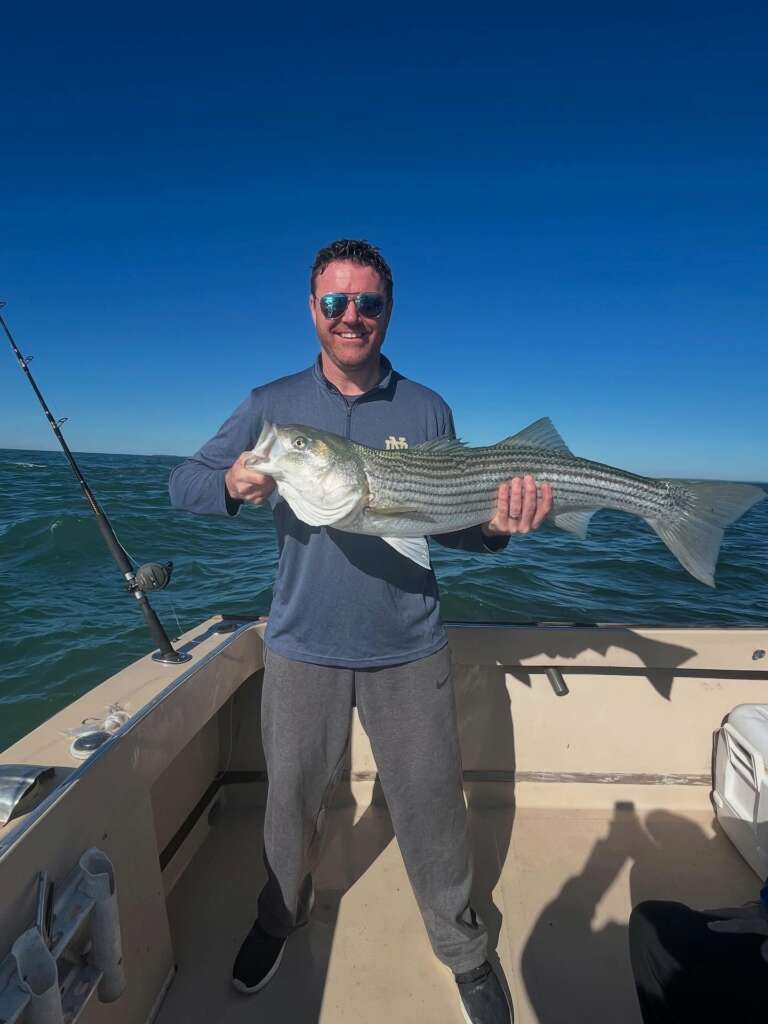 An angler holding a large striped bass caught on the trip